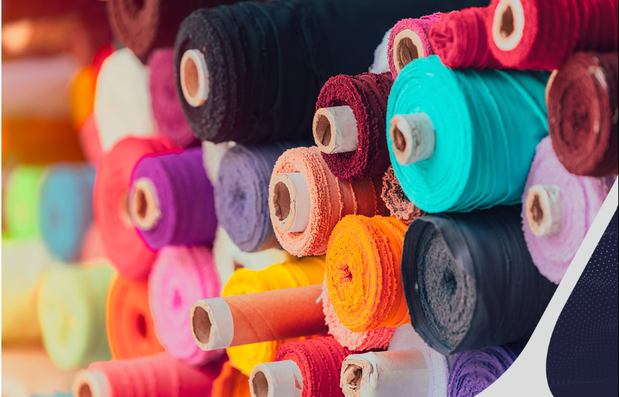 Colorful fabric rolls stacked in a textile warehouse – cotton, polyester, and blended fabric rolls for fashion, upholstery, and industrial use.