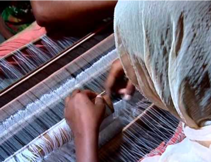 Young artisan weaving fabric by hand on a traditional loom in a textile village – showcasing handcrafted fabric production, sustainable weaving techniques, and rural textile craftsmanship